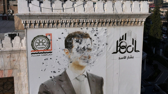 Cette photo aérienne montre un portrait criblé de balles du président syrien Bachar al-Assad ornant le bâtiment de la municipalité de Hama après qu'il a été dégradé suite à la prise de la ville par les combattants de force d'opposition, le 6 décembre 2024. 