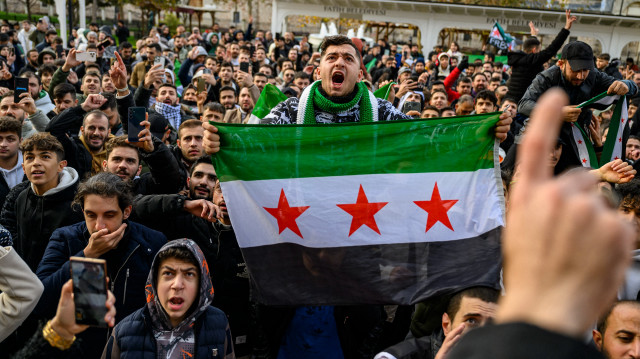 Un homme brandit un drapeau syrien alors que des résidents syriens en Türkiye célèbrent la fin du régime Baas en Syrie après que les combattants rebelles ont pris le contrôle de Damas pendant la nuit, à la mosquée Fatih, à Istanbul, le 8 décembre 2024. 