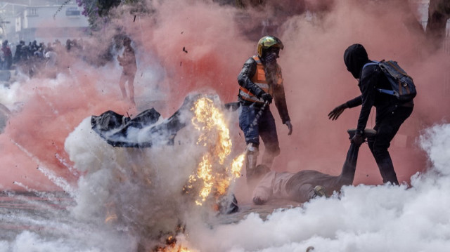 Une bombe lacrymogène explose alors que des manifestants tentent d'aider des personnes blessées devant le Parlement kenyan lors d'une grève nationale pour protester contre les hausses d'impôts et le projet de loi de finances 2024, dans le centre de Nairobi, le 25 juin 2024. 