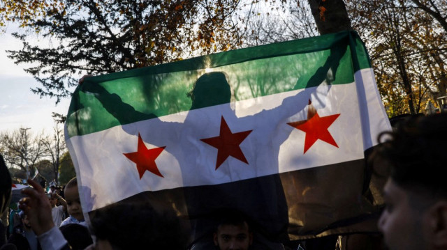 Un homme brandit le drapeau syrien lors de la célébration de la chute du président syrien Bachar al-Assad, dans le quartier de Fatih à Istanbul, le 8 décembre 2024.