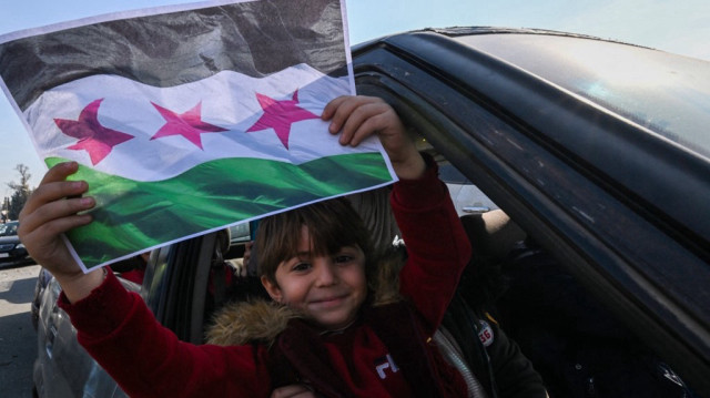 Une petite fille brandit un drapeau imprimé de l'opposition syrienne au régime de Bachar al-Assad, à Damas, le 9 décembre 2024. 