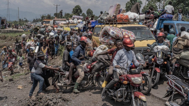 Des personnes se rassemblent sur une route fréquentée tout en transportant certains de leurs biens alors qu'elles fuient le territoire de Masisi suite aux affrontements entre les rebelles du M23 et les forces gouvernementales, sur une route près de Sake, le 7 février 2024. 