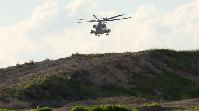 Une photo prise depuis une position dans le sud d'Israël, le long de la frontière avec la bande de Gaza, montre un hélicoptère militaire israélien survolant la frontière, le 9 février 2024.