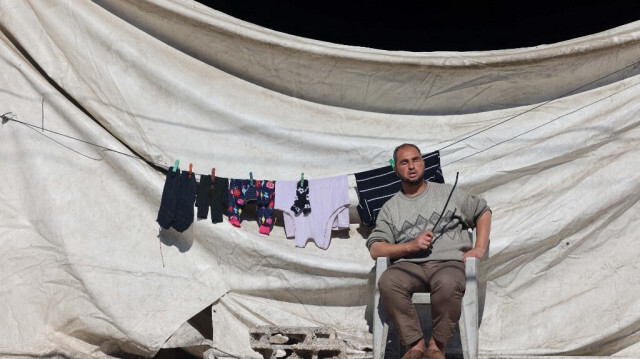 Un Palestinien aveugle est assis sur une chaise au soleil à côté d'une corde à linge près des décombres des bâtiments détruits par les bombardements israéliens à Rafah, dans le sud de la bande de Gaza, le 11 février 2024.