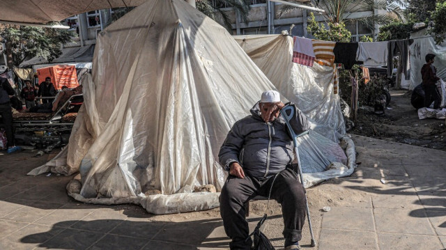 Un homme somnole en s'appuyant sur une béquille à l'extérieur d'une tente où des Palestiniens déplacés campent devant l'hôpital européen de Khan Yunis, dans le sud de la bande de Gaza, le 31 décembre 2023.