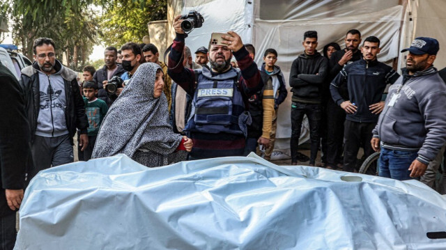 Un journaliste filme le corps d'une victime tuée par les bombardements israéliens arrivant à l'hôpital européen de Khan Younès, dans le sud de la bande de Gaza, le 31 décembre 2023.