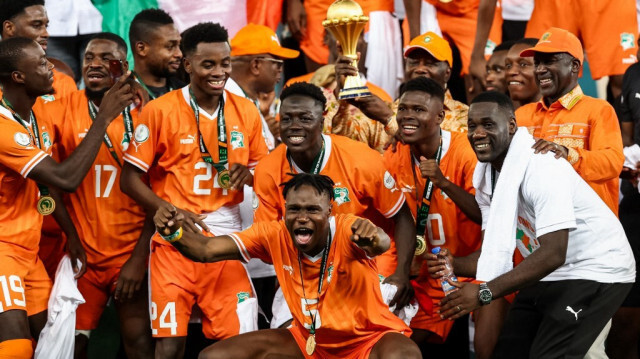 Le président de la Côte d'Ivoire Alassane Ouattara (C) soulève le trophée de la Coupe d'Afrique des Nations sur le podium après la victoire de la Côte d'Ivoire lors du match de football de la finale de la Coupe d'Afrique des Nations (CAN) 2024 entre la Côte d'Ivoire et le Nigeria au stade olympique Alassane Ouattara d'Ebimpe, à Abidjan, le 11 février 2024.