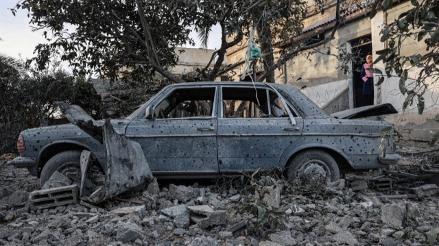 Une jeune Palestinienne se tient près d'une voiture endommagée lors des bombardements israéliens à Rafah, dans le sud de la bande de Gaza, le 12 février 2024.