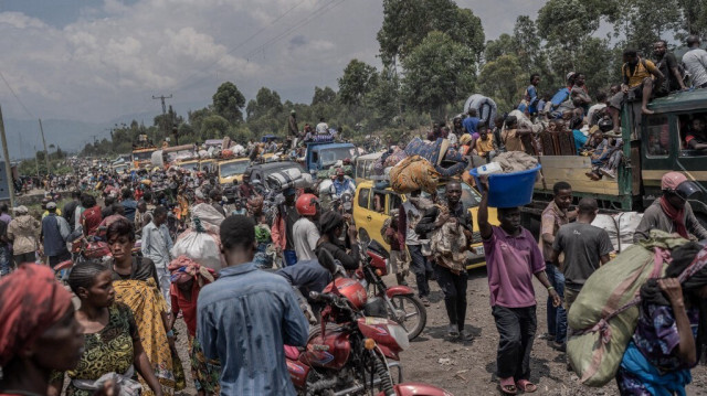 Des personnes se rassemblent sur une route fréquentée tout en transportant certains de leurs biens alors qu'elles fuient le territoire de Masisi suite aux affrontements entre les rebelles du M23 et les forces gouvernementales, sur une route près de Sake, le 7 février 2024. 