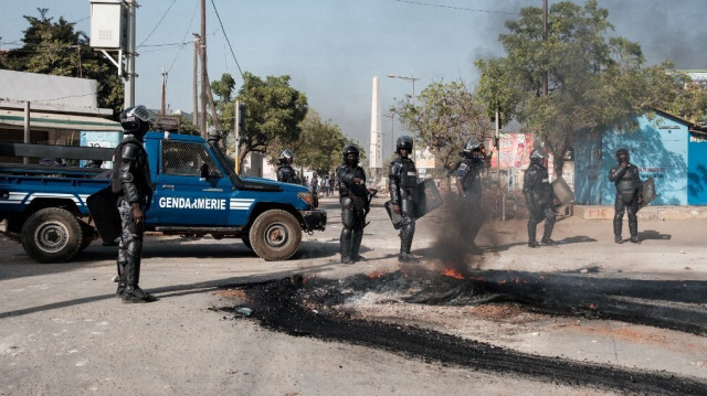 Des gendarmes nettoient les feux d'une route après des affrontements avec la police en marge d'une manifestation contre le report à la dernière minute des élections présidentielles, à Dakar, le 9 février 2024.