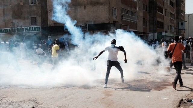 Un manifestant rejette une bombe lacrymogène lors d'affrontements avec la police en marge d'une manifestation contre le report à la dernière minute des élections présidentielles, à Dakar, au Sénégal, le 9 février 2024. 