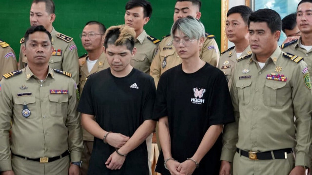 Les taïwanais Chen Neng-Chuan (centre L) et Lu Tsu-hsin (centre R) debout avec la police lors d'une conférence de presse dans la province de Preah Sihanouk, ont été condamnés à deux ans de prison, a déclaré un tribunal au Cambodge, le 16 février.