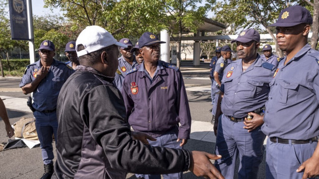 Un citoyen parle à des agents de la police sud-africaine (SAPS) lors d'un affrontement avec des manifestants à Rosebank, Johannesburg, le 21 septembre 2023.