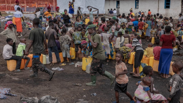 Des soldats de l'armée congolaise marchent parmi les femmes et les enfants congolais déplacés dans le camp de Bulengo, à quelques kilomètres du centre de Goma, dans l'est de la République démocratique du Congo, le 16 février 2024.