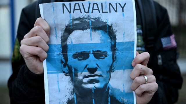 Un manifestant porte une pancarte avec la photo du défunt leader de l'opposition russe Alexei Navalny lors d'un rassemblement devant l'ambassade de Russie à Varsovie, le 16 février 2024.