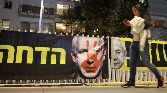 Une femme passe devant des banderoles représentant le premier ministre israélien Benjamin Netanyahu accrochées à une barrière de rue avant une manifestation anti-gouvernementale sur la place HaBima à Tel Aviv, le 10 février 2024.