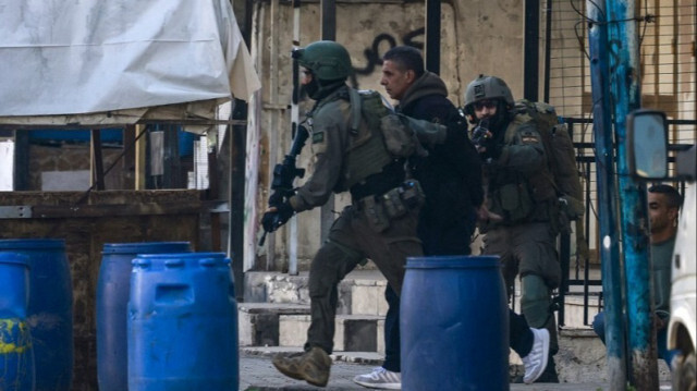 Des soldats israéliens arrêtent un homme lors d'un raid dans le camp de réfugiés d'Askar, à l'est de la ville de Naplouse en Palestine occupée, le 31 décembre 2023.