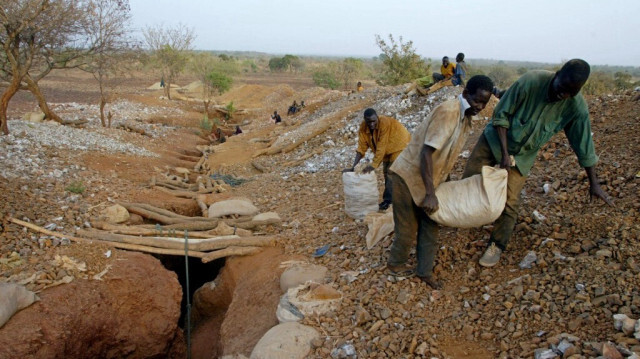 Des chercheurs d'or transportent, le 23 avril 2002, près du village de Bagassi, un sac de pierres extraits d'une mine, afin de les concasser au petit village du Sahel burkinabé, qui est devenu en peu de temps un véritable aimant pour des milliers de chercheurs d'or venus de tout le pays dans l'espoir d'y faire fortune.