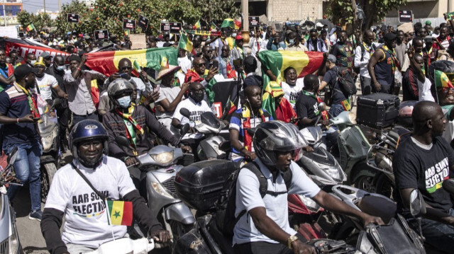 Des groupes de la société civile et des groupes politiques brandissent des pancartes et des drapeaux nationaux sénégalais lors d'une marche appelant les autorités à respecter la date des élections, à Dakar, le 17 février 2024. 