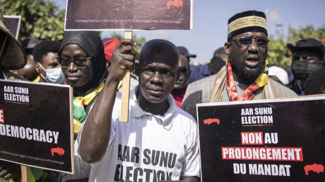 Des groupes de la société civile et des groupes politiques brandissent des pancartes lors d'une marche appelant les autorités à respecter la date de l'élection présidentielle, à Dakar, le 17 février 2024. 