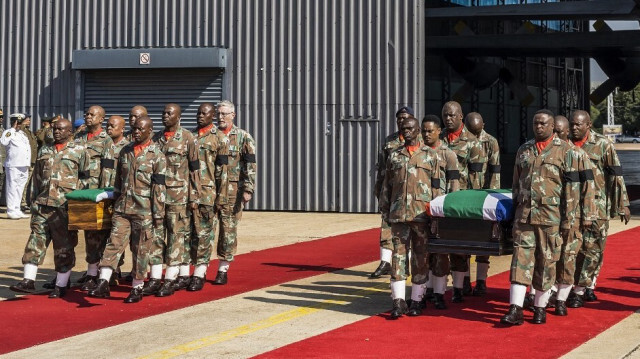 Des membres des forces de défense nationales sud-africaines (SANDF) portent les cercueils drapés du capitaine Simon Mkhulu Bone et du caporal Irven Thabang Semono lors d'une cérémonie funéraire à la base aérienne de Waterkloof, le 21 février 2024. 