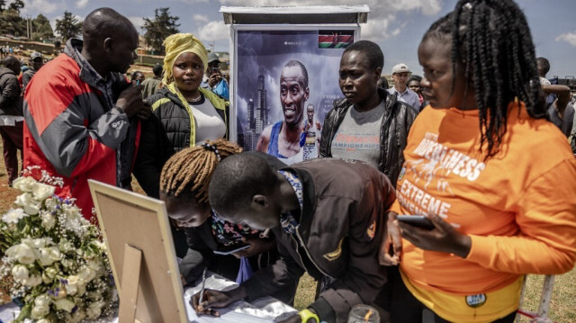 Des citoyens kényans signent un livre de condoléances à côté d'une photo de Kelvin Kiptum lors du début des cérémonies funéraires du marathonien Kelvin Kiptum à Iten, le 22 février 2024. 