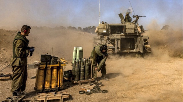 Un soldat de l'armée d'occupation israélienne transporte des munitions vers un obusier d'artillerie stationné près de la frontière de la bande de Gaza. 