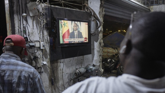 Des citoyens sénégalais regardant le président du Sénégal, Macky Sall, lors d'une conférence de presse en direct diffusée à la télévision nationale, dans le quartier de la Médina à Dakar, le 22 février 2024. 