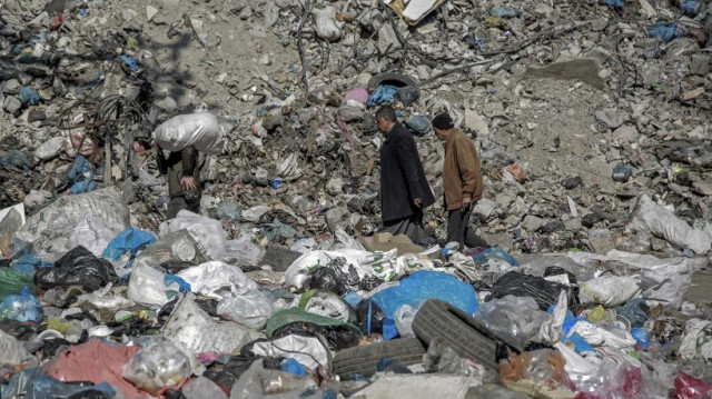 Des Palestiniens se frayent un chemin le long d'une rue jonchée d'ordures dans la ville de Gaza, le 24 février 2024.