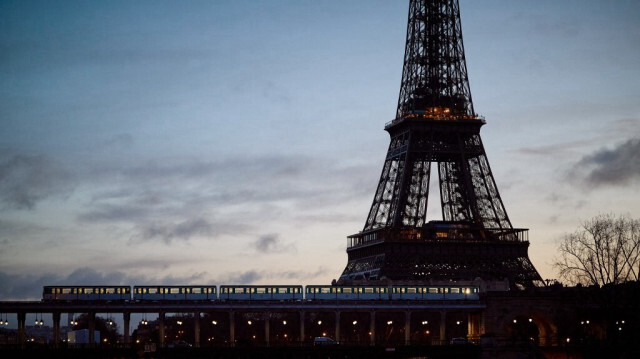 Une rame du métro parisien traverse la Seine devant la Tour Eiffel à l'aube, alors que le monument reste fermé au public pour le cinquième jour consécutif en raison de la grève du personnel, dans le centre de Paris, le 23 février 2024.