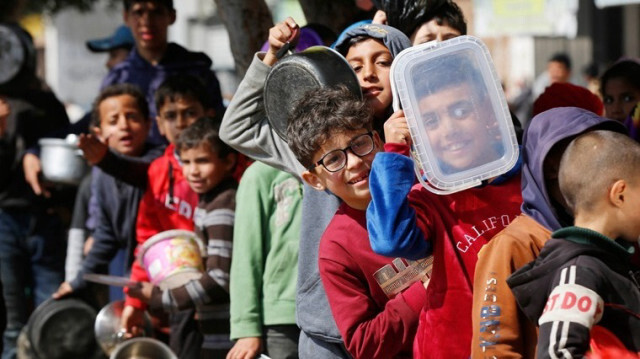 Des enfants Palestiniens, attendent dans une file d'attente de la nourriture, distribuée par des organisations caritatives à Gaza, le 24 février 2024.