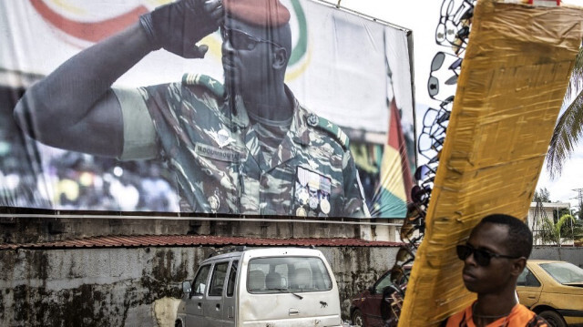 Un vendeur de lunettes de soleil passe devant un panneau d'affichage représentant le chef de la junte, le colonel Mamady Doumbouya, à Conakry, le 11 septembre 2021. 