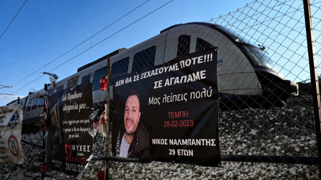 Un train hellénique passant devant des banderoles accrochées à l'endroit où 57 personnes, pour la plupart des étudiants, ont perdu la vie dans un accident de train en 2023, près de Larisa, en Grèce, le 24 février 2024.
