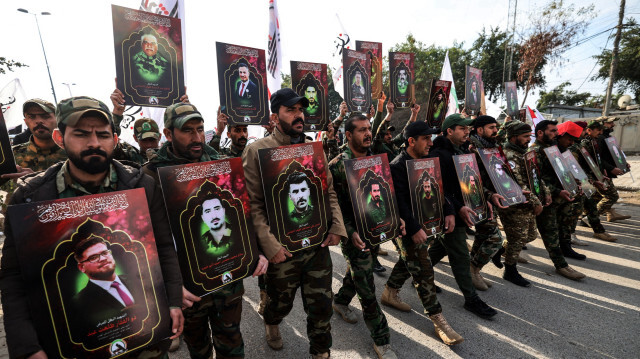 Des membres des forces paramilitaires irakiennes Hashed al-Shaabi portant les portraits de personnes tuées la veille lors de frappes américaines dans l'ouest de l'Irak, avant leur procession funéraire à Bagdad, le 4 janvier 2024.