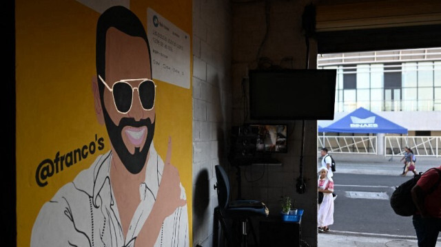 Des personnes passent devant une peinture murale représentant le président du Salvador et candidat à la réélection pour le parti Nuevas Ideas, Nayib Bukele, dans un restaurant de San Salvador, le 2 février 2024.