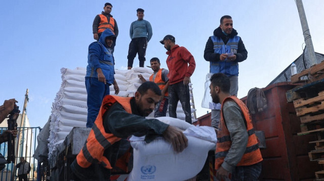 Des Palestiniens recevant des sacs de farine au centre de distribution de l'Office de secours et de travaux des Nations Unies pour les réfugiés de Palestine (UNRWA) dans le camp de réfugiés de Rafah, dans le sud de la bande de Gaza, le 21 novembre 2023.