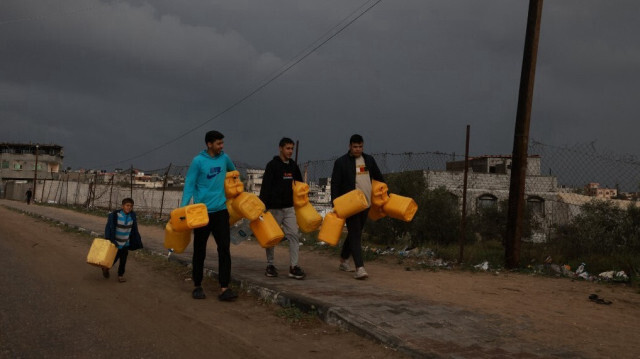 Des Palestiniens déplacés portant des jerricans pour aller chercher de l'eau à Rafah, dans le sud de la bande de Gaza, le 27 janvier 2024.