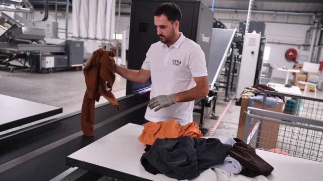 Un employé place de vieux vêtements sur la machine de tri textile au CETIA, la toute première plateforme d'innovation dédiée à la recyclabilité des textiles et des articles en cuir à Hendaye, dans le sud-ouest de la France, le 4 septembre 2023. 