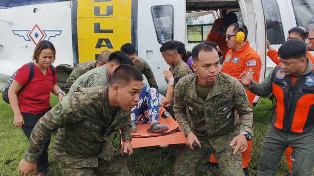 Des soldats philippins transférant un survivant de glissement de terrain d'un hélicoptère à une ambulance à la suite d'un vol d'évacuation médicale de Maco vers le centre médical régional de Davao à Tagum, dans la province de Davao del Norte.