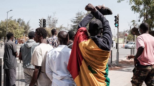 Un manifestant portant un drapeau sénégalais autour du corps fait un geste lors des affrontements avec la police à Dakar, le 9 février 2024. 