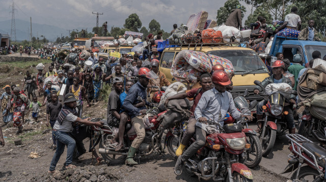 Des personnes se rassemblant sur une route fréquentée tout en transportant certains de leurs biens alors qu'elles fuient le territoire de Masisi suite aux affrontements entre les rebelles du M23 et les forces gouvernementales, sur une route près de Sake, le 7 février 2024.