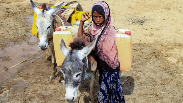 Une jeune fille yéménite utilisant des ânes pour transporter des bidons d'eau après les avoir remplis à partir d'un point de distribution dans le district d'Abs, au nord du gouvernorat de Hajjah, le 9 mars 2024.