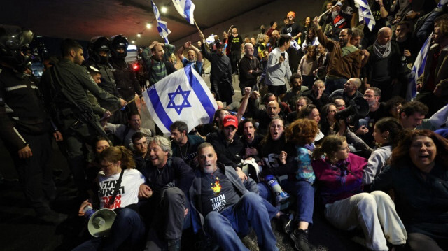 Des militants anti-gouvernementaux et des parents d'otages israéliens détenus à Gaza depuis les attaques du 7 octobre bloquent une route lors d'une manifestation à Tel Aviv le 9 mars 2024.