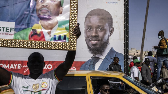 Un partisan de la coalition des candidats de l'opposition brandit un portrait devant une bannière du candidat présidentiel Bassirou Diomaye Faye lors d'un rassemblement de campagne à Dakar, au Sénégal, le 10 mars 2024.