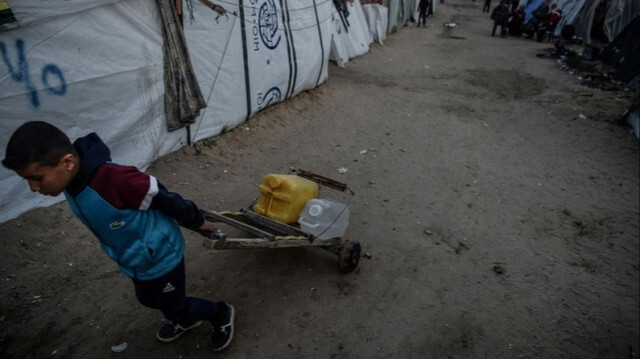 Un enfant porte des bouteilles d'eau dans des tentes de fortune installées près de la frontière égyptienne alors que les attaques israéliennes se poursuivent à Rafah dans la bande de Gaza, le 09 mars 2024.