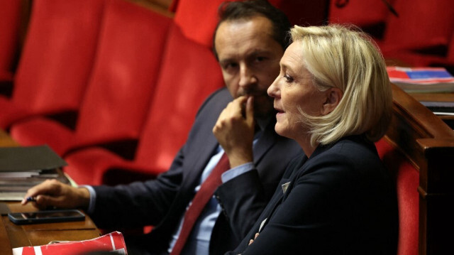 Le député français du Rassemblement national (RN) Sébastien Chenu (G) s'entretient avec la présidente du groupe parlementaire du Rassemblement national (RN) Marine Le Pen lors d'une séance de questions au gouvernement à l'Assemblée nationale à Paris, le 12 mars 2024.