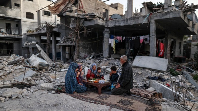 Une famille Palestinienne prend le premier repas de rupture du jeûne (Iftar) dans les décombres de leur maison détruite par les attaques israéliennes à Gaza, le 11 mars 2024.