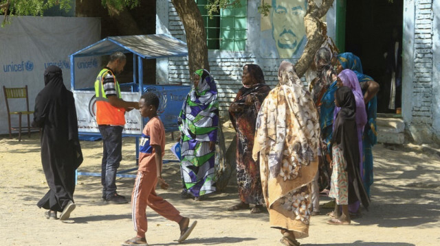 Des Soudanais déplacés discutent avec un travailleur humanitaire lors d'une livraison d'aide humanitaire dans une école, où les familles se sont réfugiées, près de la ville de Gadaref, dans le Soudan déchiré par la guerre, le 6 mars 2024.