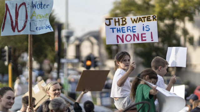 Des habitants brandissent des pancartes lors d'une manifestation contre le manque d'accès à l'eau dans le quartier de Blairgowrie, à Johannesburg, le 12 mars 2024.