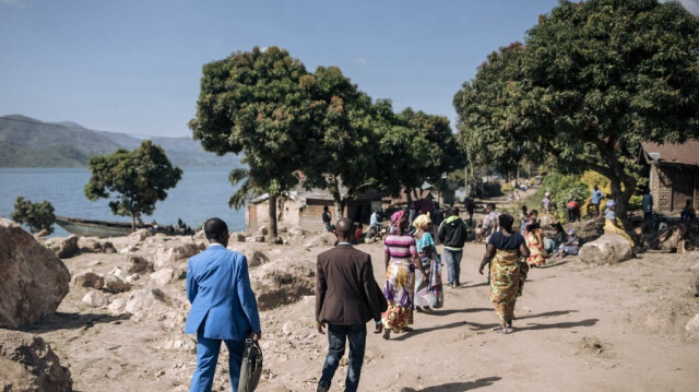Des habitants marchent dans un glissement de terrain de boue et de roches dans le village de Bushushu sur les rives du lac Kivu dans le territoire de Kalehe, dans la province du Sud-Kivu, à l'est de la République démocratique du Congo, le 9 juin 2023.